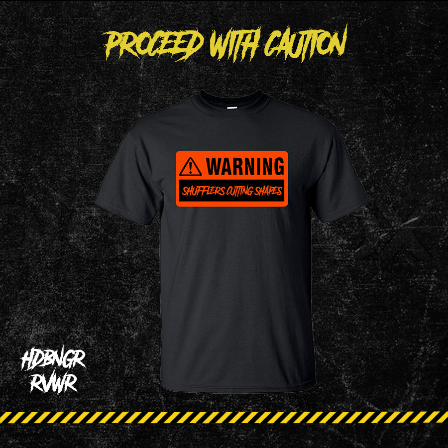 Black-shirt with text graphic 'WARNING: SHUFFLERS CUTTING SHAPES' on the front.