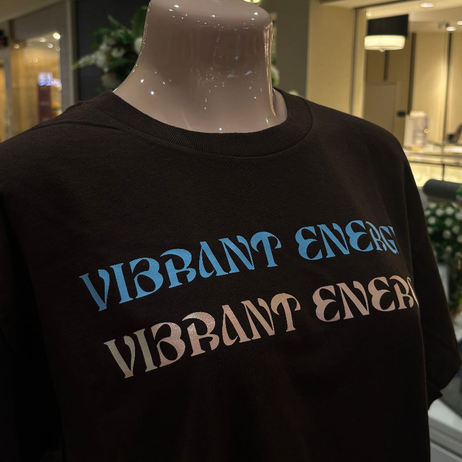 Dark Brown t-shirt with 'Vibrant Energy' text on a mannequin in a store setting.