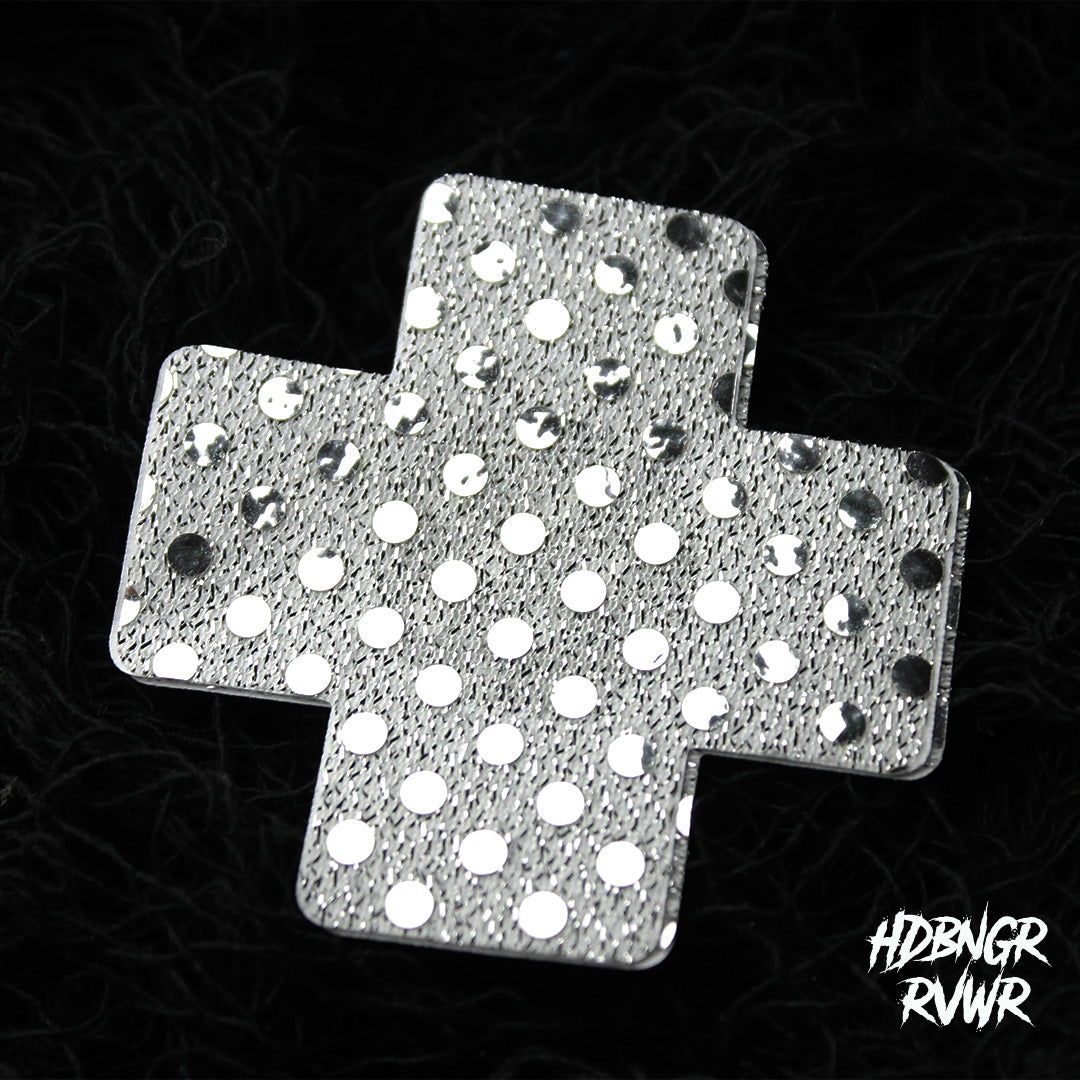 Single silver sequin cross-shaped pastie with mirror dot embellishment on dark textured background — Silver Xs by HDBNGR RVWR.