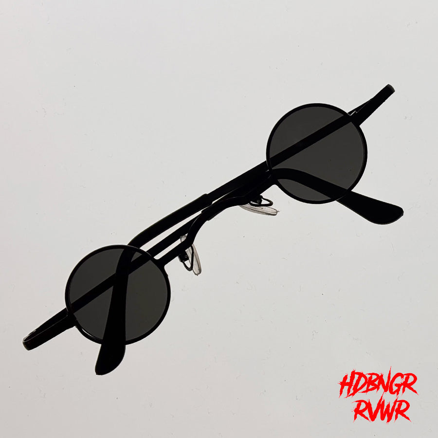 Black round-frame sunglasses with dark lenses, photographed against a plain light background. A red stylized text watermark reading 'HDBNGR RWVR' appears in the bottom-right corner.