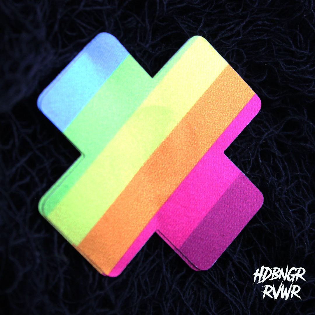 Single rainbow stripe cross-shaped pastie in neon pink, orange, yellow, green and blue on dark background — Kiss the Rainbow by HDBNGR RVWR.
