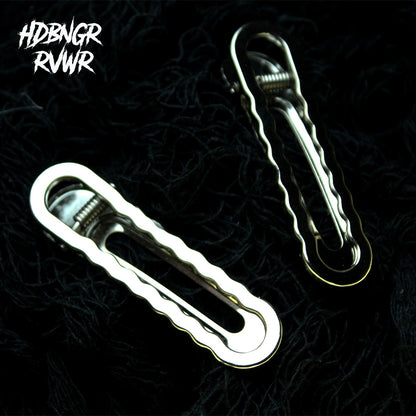 Two silver wavy-edge elongated hair clips laid on a dark textured background with HDBNGR RVWR watermark — Abyss Waves V1.