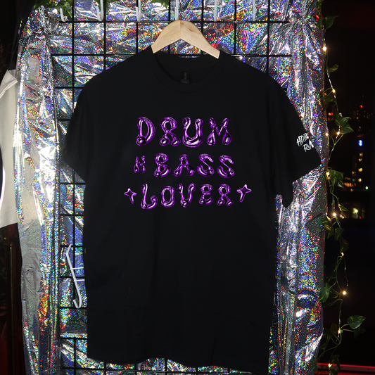 Black t-shirt with 'HARD TECHNO LOVER' text on a hanger against a reflective, multicolored background.