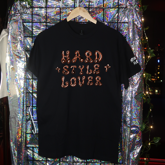 Black t-shirt with 'TECHNO LOVER' text on a hanger against a reflective, multicolored background.