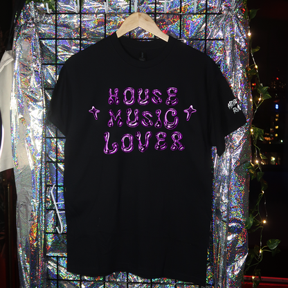 Black t-shirt with 'HARD TECHNO LOVER' text on a hanger against a reflective, multicolored background.