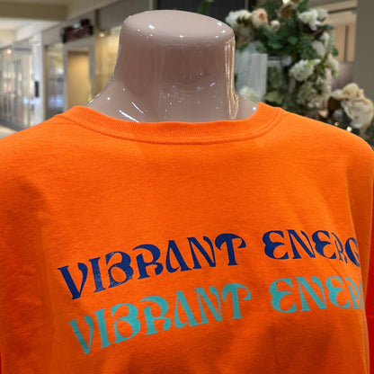 Orange sweatshirt with 'Vibrant Energy' text on a mannequin in an indoor setting.