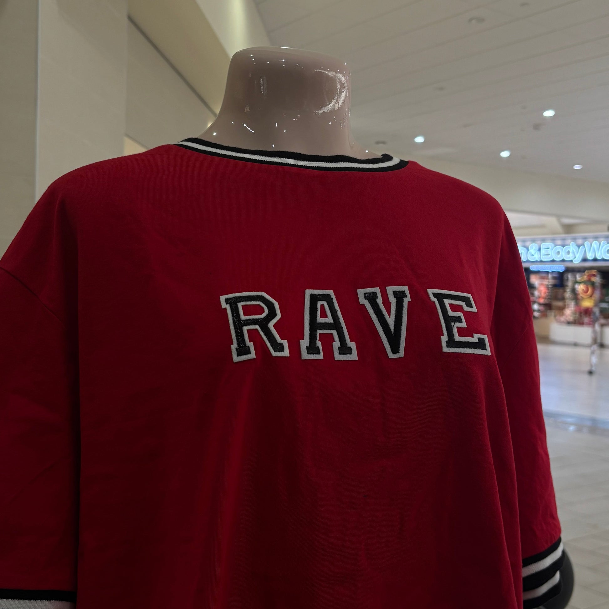 Red garment with 'RAVE' text on a mannequin against a white wall.